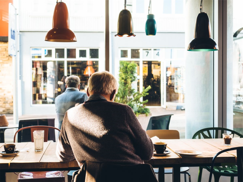 Professional senior man in cafe looking out large windows