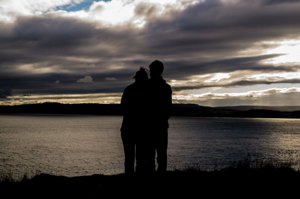 Photo of couple standing at the edge of a lake
