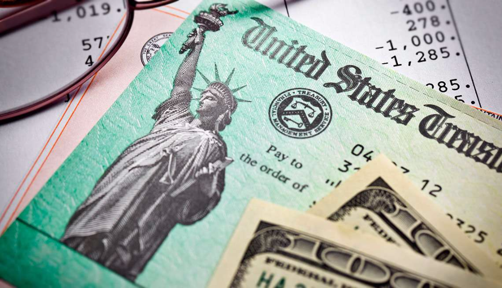 Photo showing taxes, IRS refund check, and two $100 dollar bills