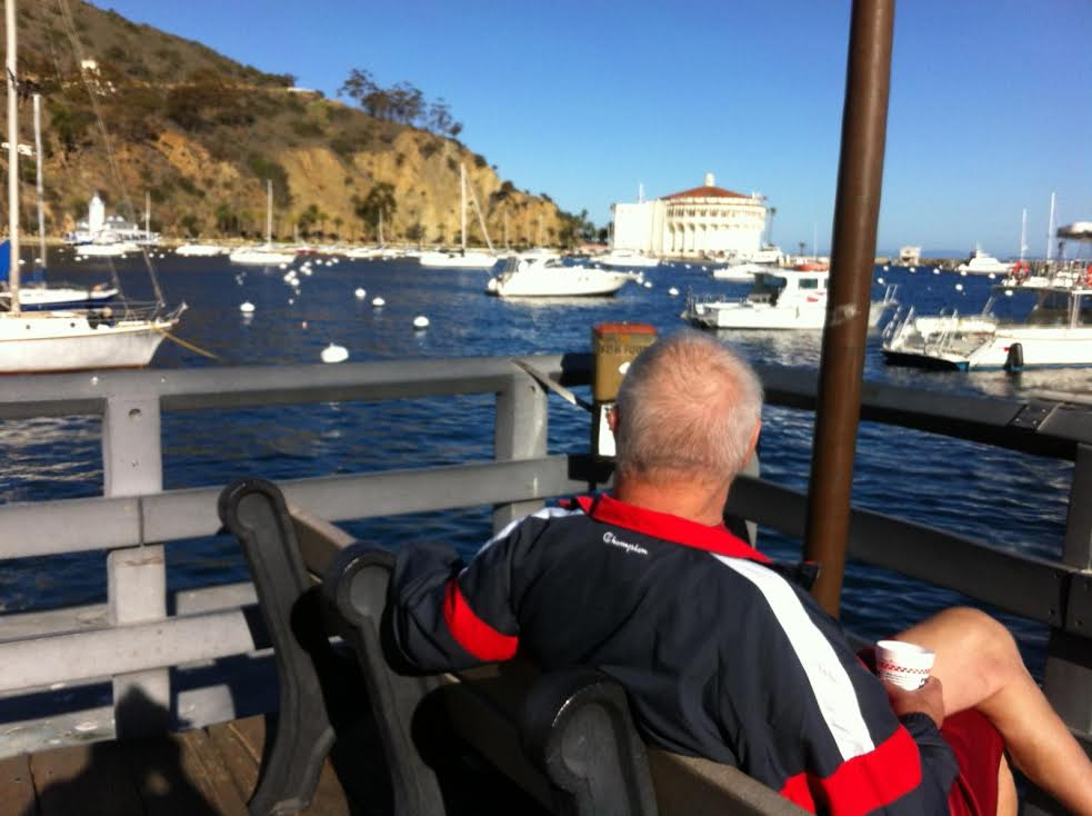 Sporty senior man with coffee on bench looking out over marina