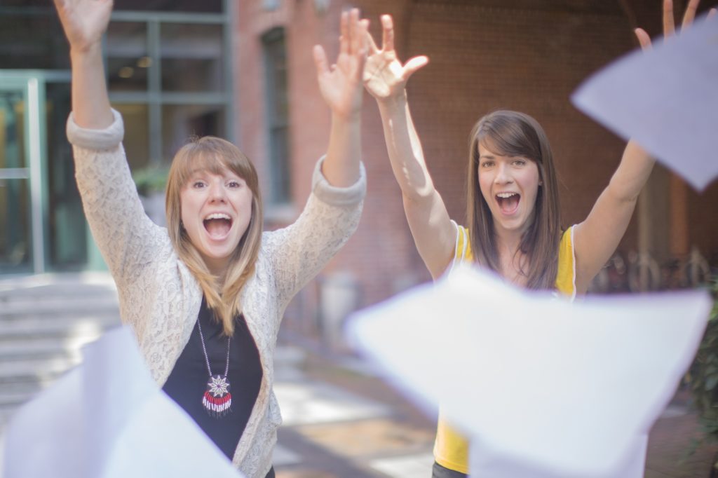 Photo of two young women throwing paper