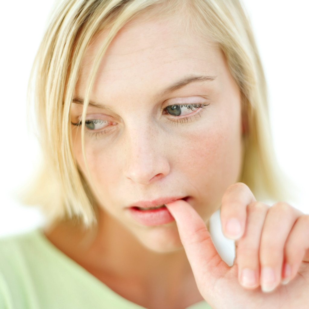 Photo of young blond woman biting her thumb nail